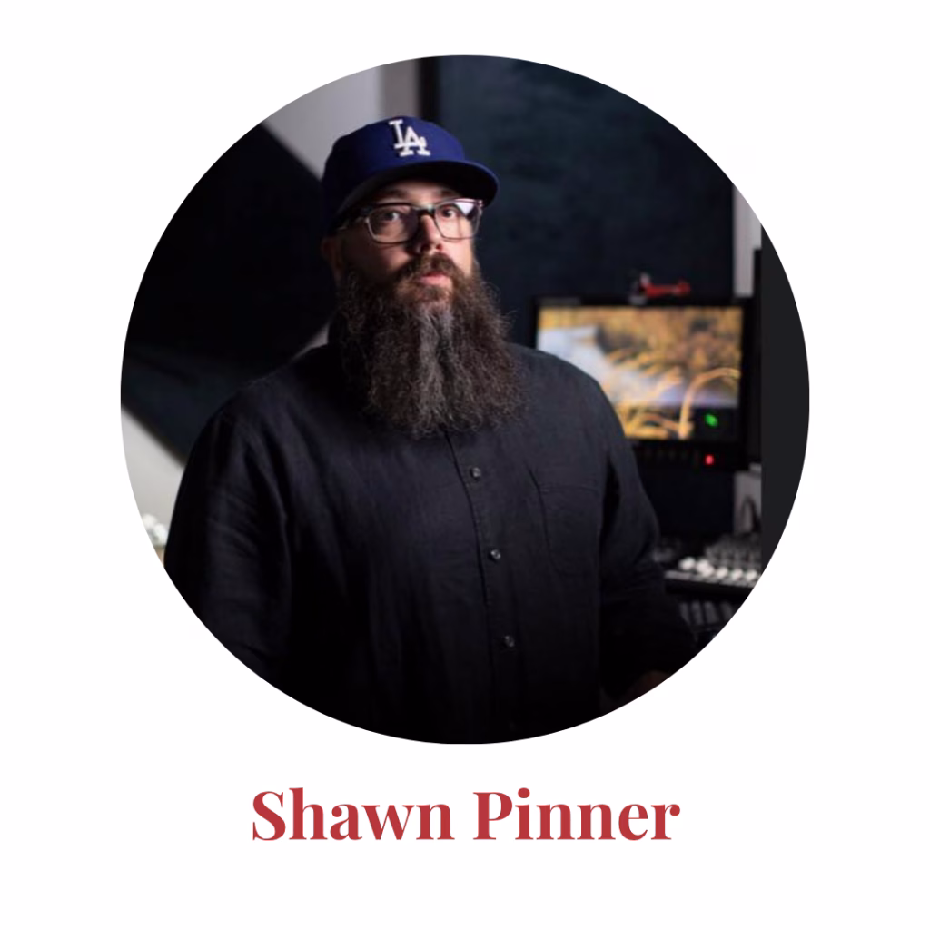 A man with a long beard wearing glasses, a blue LA baseball cap, and a black shirt stands in a studio with a computer and audio equipment. Text below reads: Shawn Pinner.