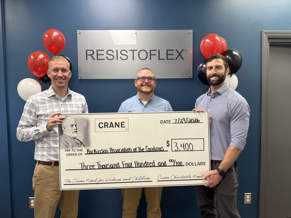 Three smiling men hold a large check for $3,400 to the Parkinson Association of the Carolinas, with balloons and a Resistoflex sign in the background.